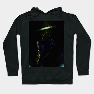 Digital collage and special processing. Person looking on his hand. Bizarre, dark. Green and blue. Hoodie